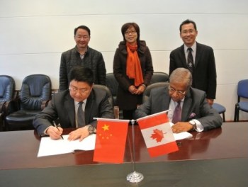 Chair of the BCIT Board of Governors, Taj Mitha (seated, right), signs a MOU as Dean of BCIT International Lawrence Gu (standing, right) and members of the Chinese delegation look on.