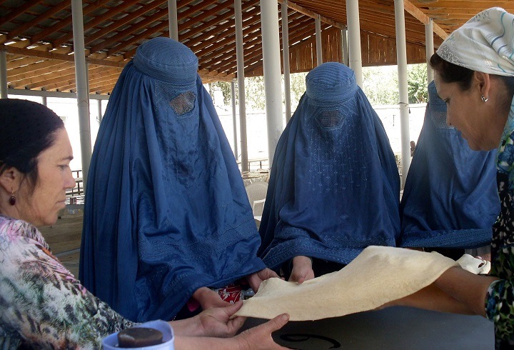 Tajik women teach veiled Afghan women how to bake traditional bread in a tandoor oven in Darvoz, Tajikistan, in June. [Central Asia Online/Nadin Bahrom]