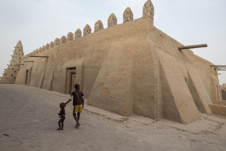 Two boys walk past Djinguereber. Locals say if the mosques are all destroyed, the world will end. Photograph: Sean Smith via The Guardian  