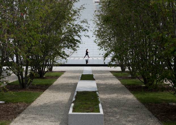 A woman walking past is framed by serviceberry trees in Aga Khan Park. (Darren Calabrese for The Globe and Mail)