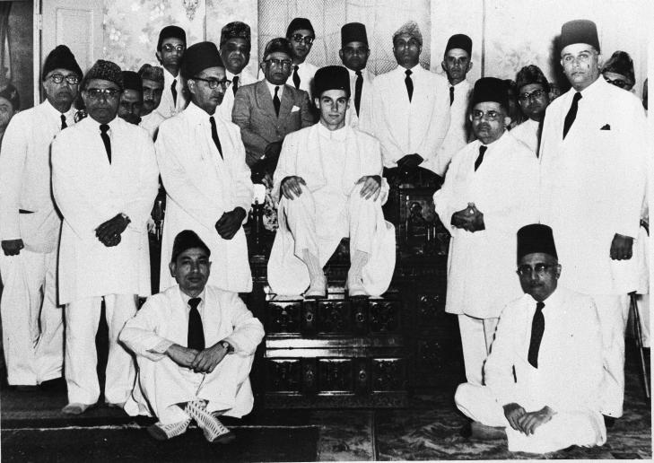 The new Aga Khan, seated at center, and former Prince Karim, grandson of the late Aga Khan, sits among his followers of the Ismaili Muslims in Bombay, India, Aug. 20, 1957. (AP Photo)