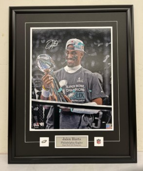 Celebrate the Philadelphia Eagles' historic Super Bowl LIX victory with this Jalen Hurts Deluxe Framed autographed 16" x 20" Lombardi Trophy Presentation Photograph. This stunning image captures the exhilarating moment when Hurts hoisted the coveted trophy after his MVP performance. It's a must-have for any Philly fan eager to relive the magic of their championship season. Image credit: Al Dhalla