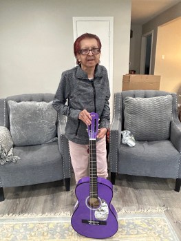 Naz Dhalla holding this year's feature item in the 2025 Chicago Rita Hayworth Gala silent auction, autographed purple guitar from Taylor Swift. Image credit: Al Dhalla